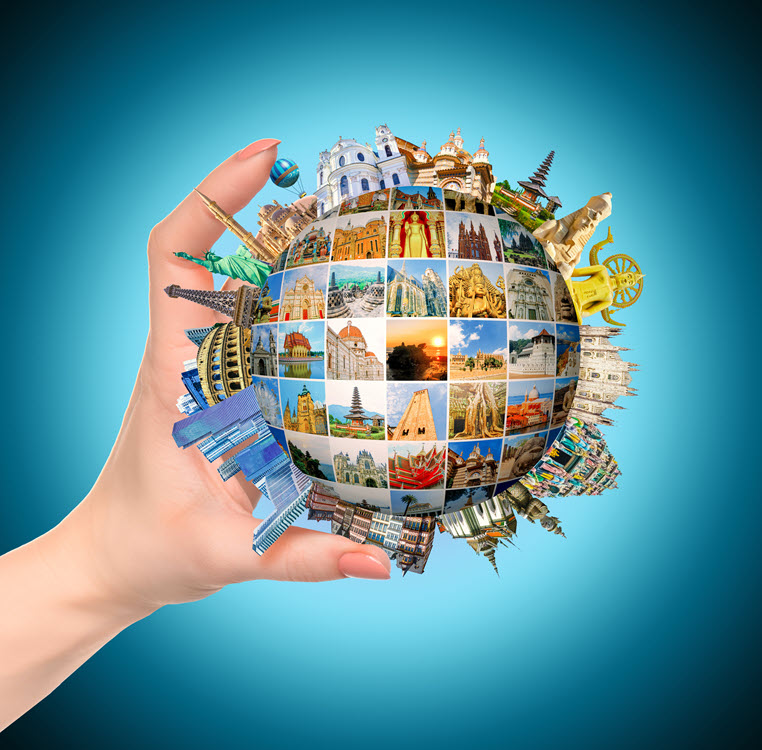 Hand holding a globe featuring architectural icons from around the world.